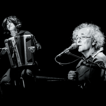 Photographie en noir et blanc de l'artiste Barzingault accompagné d'un accordéoniste. 