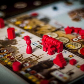 Plateau de jeu de société stratégique parsemé de nombreuses pièces en bois rouge.