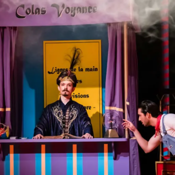 Photographie d'un magicien regardant face à lui et à ses côtés, un homme touchant du doigt une boule de cristal.