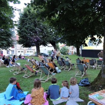 Ciné plein air, transats installés au beau milieu d'une pelouse avec des personnes installés confortablement