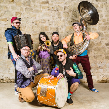 Fanfare Moussaka, musiciens et musiciennes photographiés avec leurs instruments dans une allure décontractée et joviale. 