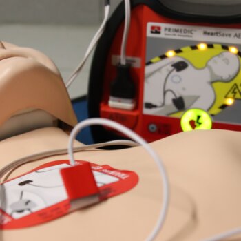 Un mannequin d'entraînement aux premiers secours est équipé d'électrodes reliées à un défibrillateur automatisé.